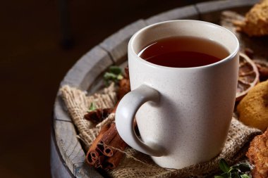 Kavramsal şenlikli bileşimi ile bir fincan sıcak çay, kurabiye ve spicies bir ahşap varil, seçici odak, yakın çekim