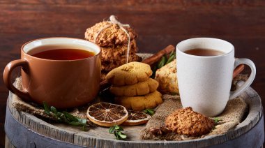 Sıcak çay, kurabiye ve spicies ahşap varil, seçici odak, yakın çekim iki bardak kavramsal şenlikli kompozisyon