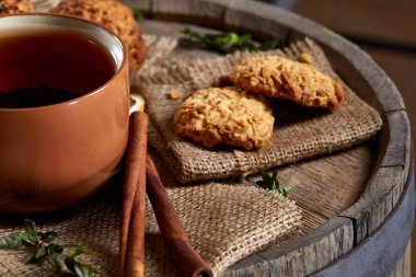 Kavramsal şenlikli bileşimi ile bir fincan sıcak çay, kurabiye ve spicies bir ahşap varil, seçici odak, yakın çekim