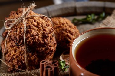 Kavramsal şenlikli bileşimi ile bir fincan sıcak çay, kurabiye ve spicies bir ahşap varil, seçici odak, yakın çekim