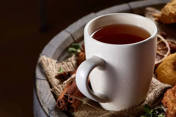 Kavramsal şenlikli bileşimi ile bir fincan sıcak çay, kurabiye ve spicies bir ahşap varil, seçici odak, yakın çekim