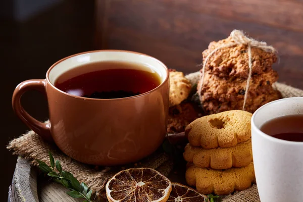 Composição festiva conceitual com duas xícaras de chá, biscoitos e espiões em um barril de madeira, foco seletivo, close-up — Fotografia de Stock