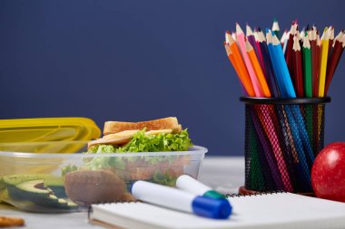 Beyaz masa, seçici odak sağlıklı öğle yemeği kutusu ve okul malzemeleri ile okul öğle yemeği molası kavramı.