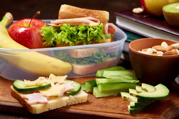 Okul veya sandviç ile öğle yemeği kutusu ve çeşitli renkli sebze ve meyve ahşap arka plan üzerinde piknik, yakın çekim. Sağlıklı beslenme alışkanlıkları kavramı. Rustik ahşap zemin üzerine diyet kompozisyon