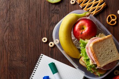 Okul veya sandviç ile öğle yemeği kutusu ve çeşitli renkli sebze ve meyve ahşap arka plan üzerinde piknik, yakın çekim.