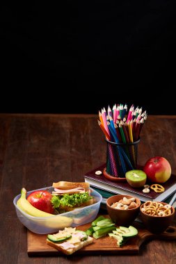 Okul veya sandviç ile öğle yemeği kutusu ve çeşitli renkli sebze ve meyve ahşap arka plan üzerinde piknik, yakın çekim.