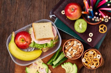 Okul veya sandviç ile öğle yemeği kutusu ve çeşitli renkli sebze ve meyve ahşap arka plan üzerinde piknik, yakın çekim.