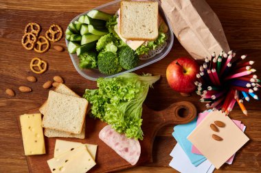 Okul öğle yemeği molası ile sağlıklı öğle yemeği kutusu ve okul malzemeleri ahşap masa, seçici odak kavramı.