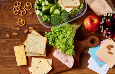 Okul öğle yemeği molası ile sağlıklı öğle yemeği kutusu ve okul malzemeleri ahşap masa, seçici odak kavramı.