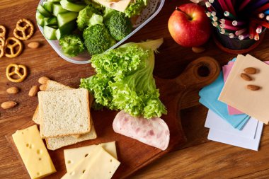 Okul öğle yemeği molası ile sağlıklı öğle yemeği kutusu ve okul malzemeleri ahşap masa, seçici odak kavramı.