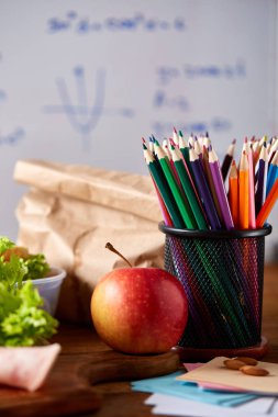 Geri okul kavramı, okul malzemeleri, bisküvi, paket öğle yemeği ve beslenme çantası beyaz yazı tahtası, seçici odak üzerinde.