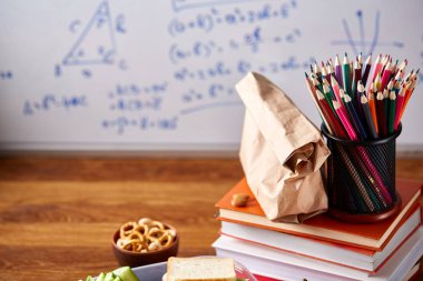 Geri okul kavramı, okul malzemeleri, bisküvi, paket öğle yemeği ve beslenme çantası beyaz yazı tahtası, seçici odak üzerinde.