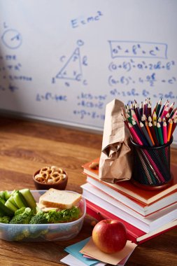 Geri okul kavramı, okul malzemeleri, bisküvi, paket öğle yemeği ve beslenme çantası beyaz yazı tahtası, seçici odak üzerinde.