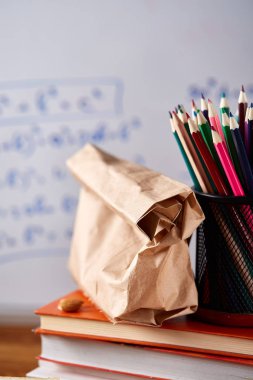 Geri okul kavramı, okul malzemeleri, bisküvi, paket öğle yemeği ve beslenme çantası beyaz yazı tahtası, seçici odak üzerinde.