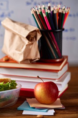 Geri okul kavramı, okul malzemeleri, bisküvi, paket öğle yemeği ve beslenme çantası beyaz yazı tahtası, seçici odak üzerinde.