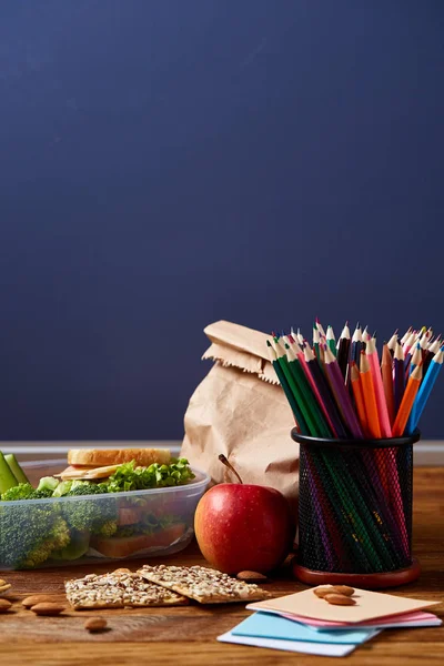 Back to School concept, school supplies, biscuits and lunchbox on wooden desk, selective focus, close-up. — Stock Photo, Image