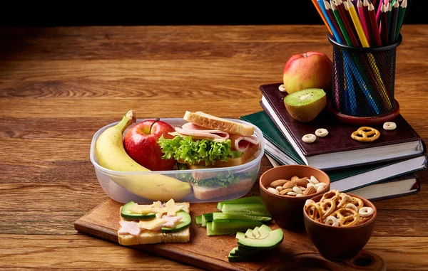 School of picknick doos van de lunch met broodje en diverse kleurrijke groenten en fruit op houten achtergrond, close-up. — Stockfoto