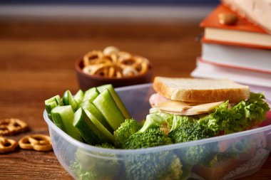 Okul öğle yemeği molası ile sağlıklı öğle yemeği kutusu ve okul malzemeleri ahşap masa, seçici odak kavramı.