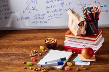 Geri okul kavramı, okul malzemeleri, bisküvi, paket öğle yemeği ve beslenme çantası beyaz yazı tahtası, seçici odak üzerinde.