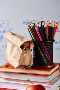 Geri okul kavramı, okul malzemeleri, bisküvi, paket öğle yemeği ve beslenme çantası beyaz yazı tahtası, seçici odak üzerinde.