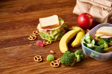 Okul öğle yemeği molası ile sağlıklı öğle yemeği kutusu ve okul malzemeleri ahşap masa, seçici odak kavramı.