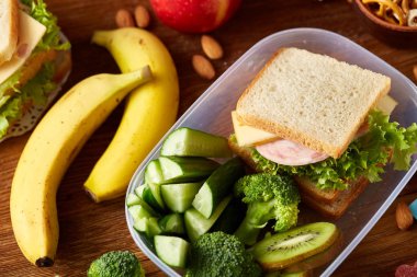 Okul öğle yemeği molası ile sağlıklı öğle yemeği kutusu ve okul malzemeleri ahşap masa, seçici odak kavramı.