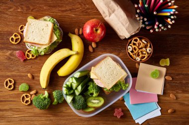 Okul öğle yemeği molası ile sağlıklı öğle yemeği kutusu ve okul malzemeleri ahşap masa, seçici odak kavramı.