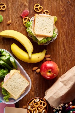 Okul öğle yemeği molası ile sağlıklı öğle yemeği kutusu ve okul malzemeleri ahşap masa, seçici odak kavramı.