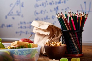 Geri okul kavramı, okul malzemeleri, bisküvi, paket öğle yemeği ve beslenme çantası beyaz yazı tahtası, seçici odak üzerinde.