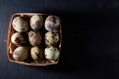 Bıldırcın yumurtası içinde bir koyu siyah arka plan, üstten görünüm, seçici odak, arkadan bir sille.