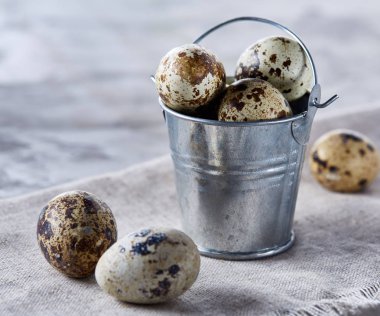Küçük dekoratif kova peçete bıldırcın yumurtalarının dolu beyaz dokulu arka plan, yakın çekim, seçici odak üzerinde.