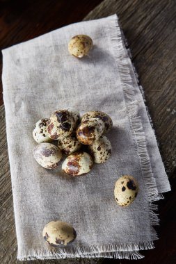 Piramit peçeteye Şimşir dalları ile düzenlenmiş bir ahşap masa, yakın çekim, seçici odak üzerinde bıldırcın yumurtası.