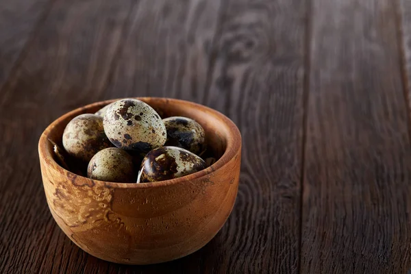 Bir koyu ahşap arka plan, üstten görünüm, yakın çekim bir ahşap kase taze bıldırcın yumurtası