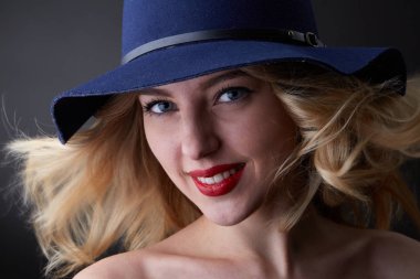 Seksi sarışın kadın düşük anahtar portresi, giyen bir şapka, kamera seyir, stüdyo, arka plan bulanık, gün ışığı vurdu