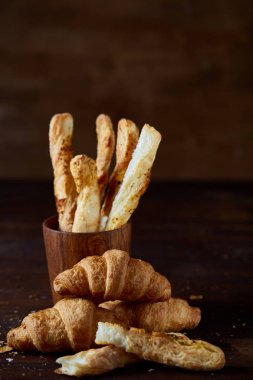 Bir eski ahşap masa, yakın çekim, seçici odak, sığ derinlik-in tarla lezzetli tereyağı kruvasan.