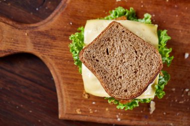Lezzetli ve taze sandviç kesme tahtası üzerinde bir koyu ahşap arka plan üzerinde yakın çekim