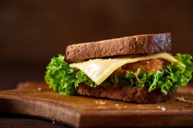 Lezzetli ve taze sandviç kesme tahtası üzerinde bir koyu ahşap arka plan üzerinde yakın çekim