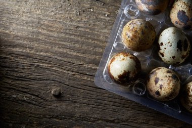 Bıldırcın yumurtası koyu ahşap arka plan, üstten görünüm, seçici odak plastik bir kap içinde