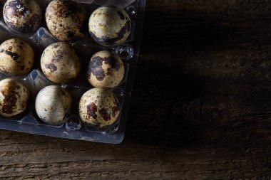 Bıldırcın yumurtası koyu ahşap arka plan, üstten görünüm, seçici odak plastik bir kap içinde