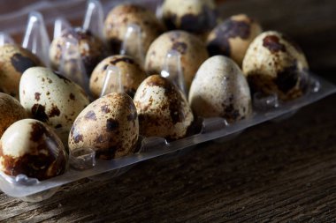 Bıldırcın yumurtası koyu ahşap arka plan, üstten görünüm, seçici odak plastik bir kap içinde