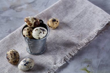 Küçük dekoratif kova peçete bıldırcın yumurtalarının dolu beyaz dokulu arka plan, yakın çekim, seçici odak üzerinde.