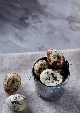 Küçük dekoratif kova peçete bıldırcın yumurtalarının dolu beyaz dokulu arka plan, yakın çekim, seçici odak üzerinde.