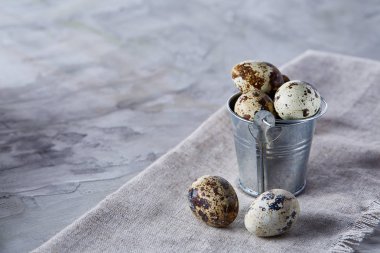 Küçük dekoratif kova peçete bıldırcın yumurtalarının dolu beyaz dokulu arka plan, yakın çekim, seçici odak üzerinde.