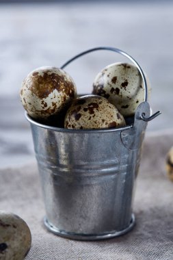 Küçük dekoratif kova peçete bıldırcın yumurtalarının dolu beyaz dokulu arka plan, yakın çekim, seçici odak üzerinde.