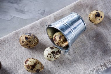 Devrilmiş dekoratif kova peçete bıldırcın yumurtalarının dolu beyaz dokulu arka plan, yakın çekim, seçici odak üzerinde.