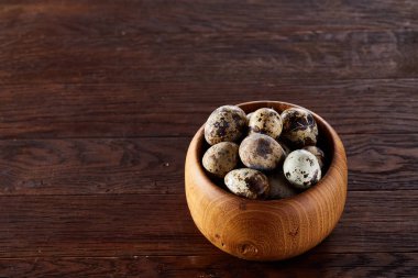 Bir koyu ahşap arka plan, üstten görünüm, yakın çekim bir ahşap kase taze bıldırcın yumurtası