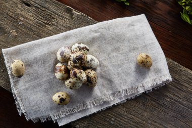 Piramit peçeteye Şimşir dalları ile düzenlenmiş bir ahşap masa, yakın çekim, seçici odak üzerinde bıldırcın yumurtası.