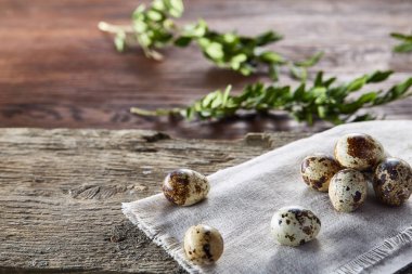 Piramit peçeteye Şimşir dalları ile düzenlenmiş bir ahşap masa, yakın çekim, seçici odak üzerinde bıldırcın yumurtası.