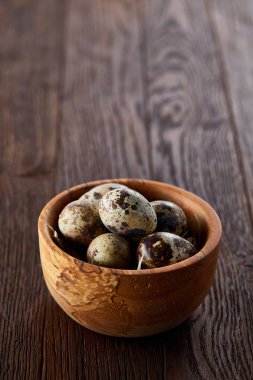 Bir koyu ahşap arka plan, üstten görünüm, yakın çekim bir ahşap kase taze bıldırcın yumurtası