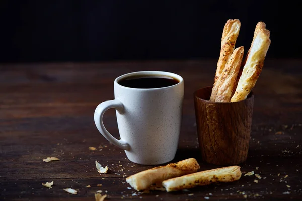 Taza de café y palitos de pan sobre un viejo fondo de madera, primer plano, enfoque selectivo . — Foto de Stock